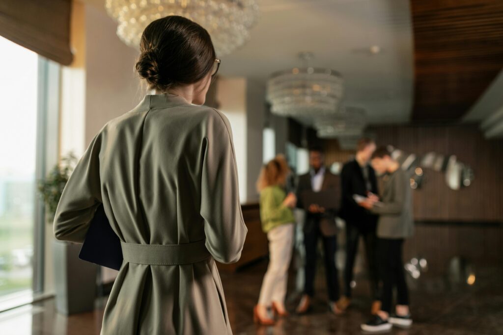 A woman seen from behind entering a hotel lobby while holding a laptop, representing brand presence in a physical space.
