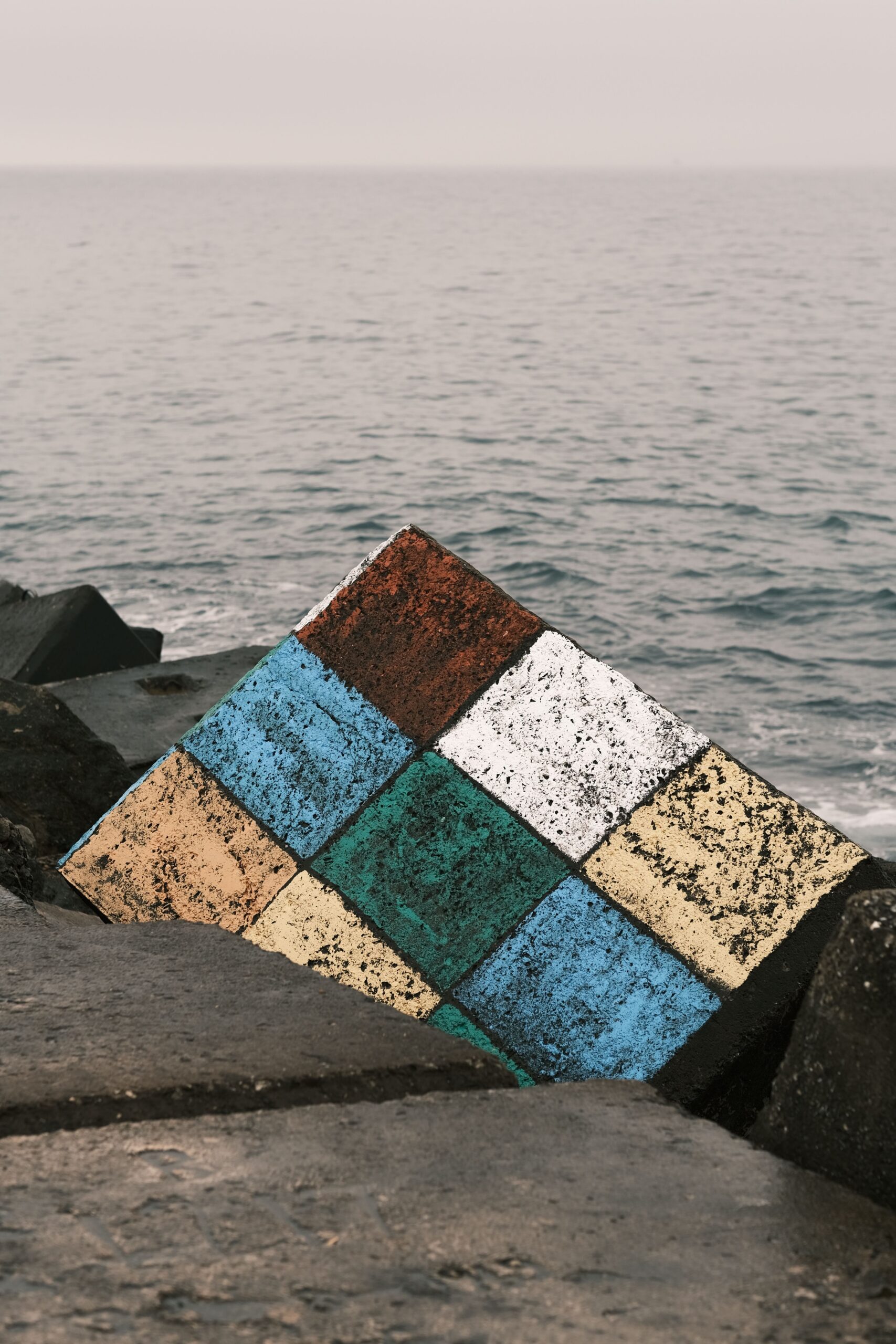 Rocky coastline featuring a large cube-like structure emerging from the natural landscape.