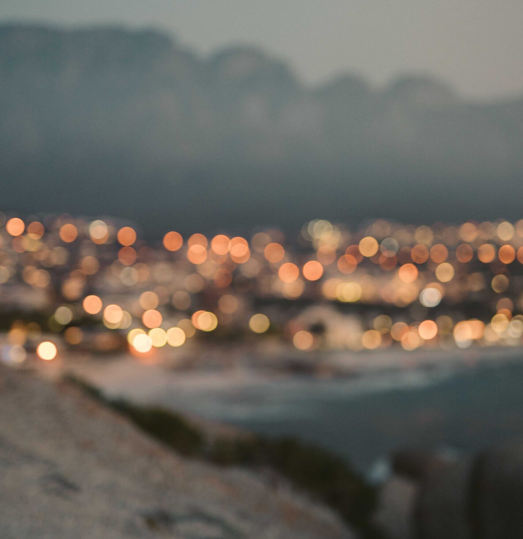 Distant lights glowing across a coastal landscape at sunset.