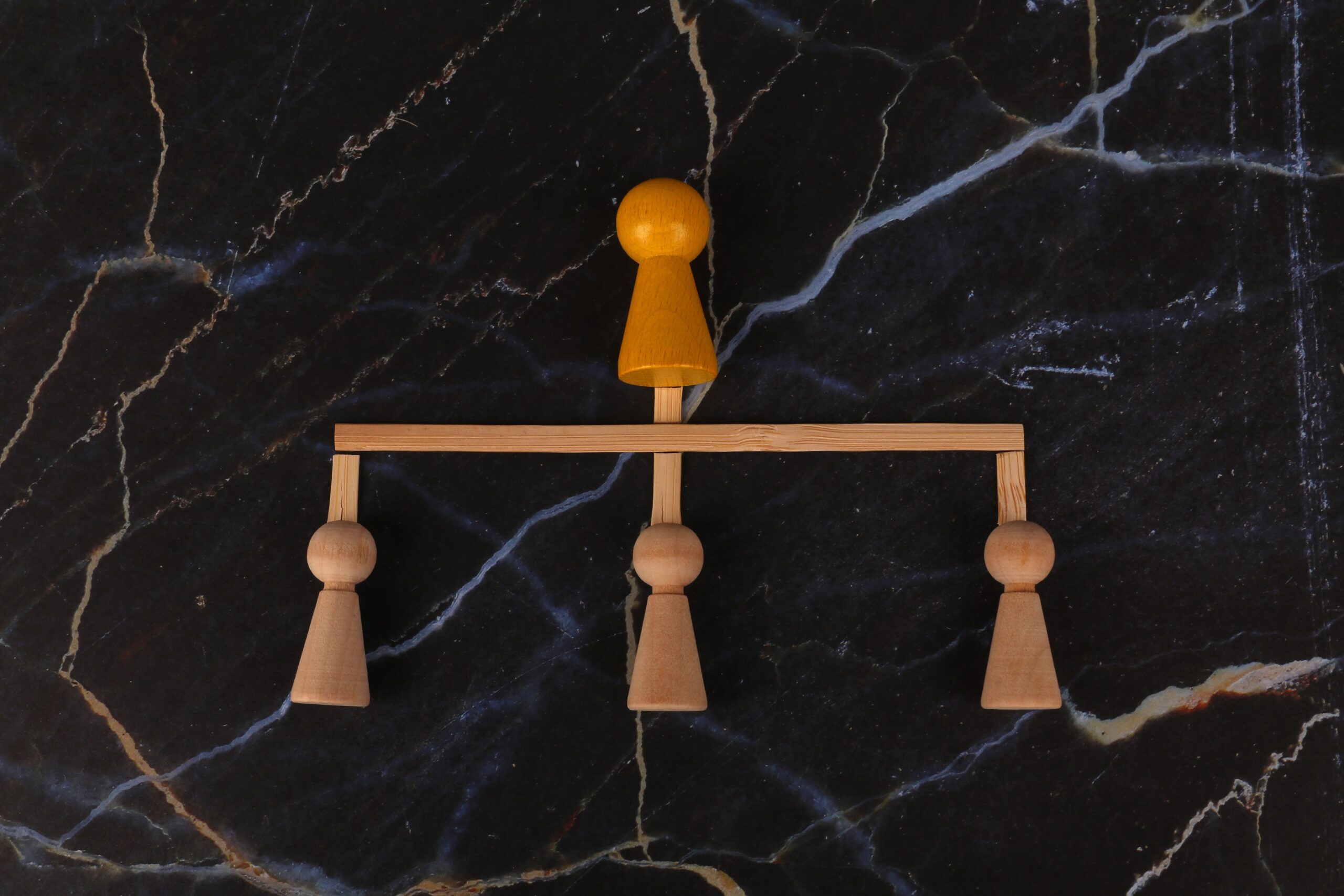 Chess piece balanced above three other chess pieces on a balance scale.